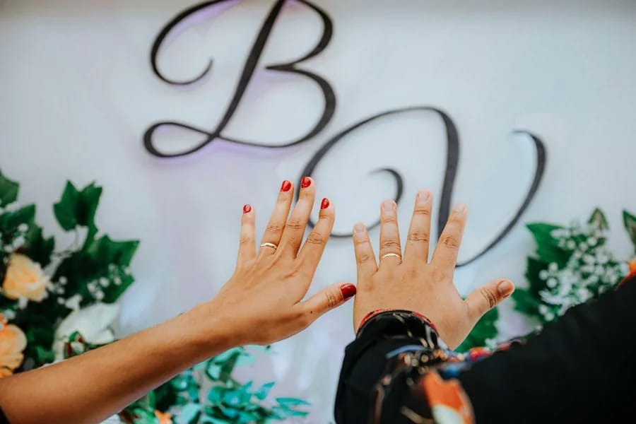 Dua tangan bersentuhan di depan dinding monogram bunga