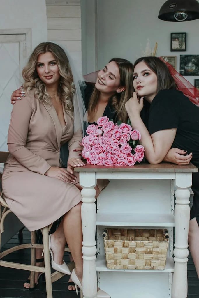Tiga perempuan berpose bersama buket bunga merah muda